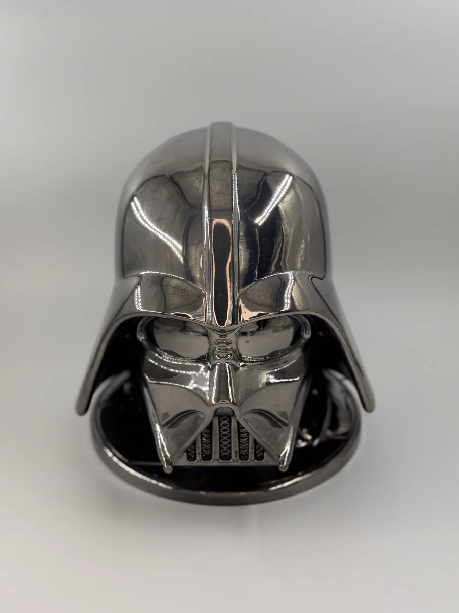 Un casque décoratif imprimé en 3D, finition chromée, posé sur un fond gris